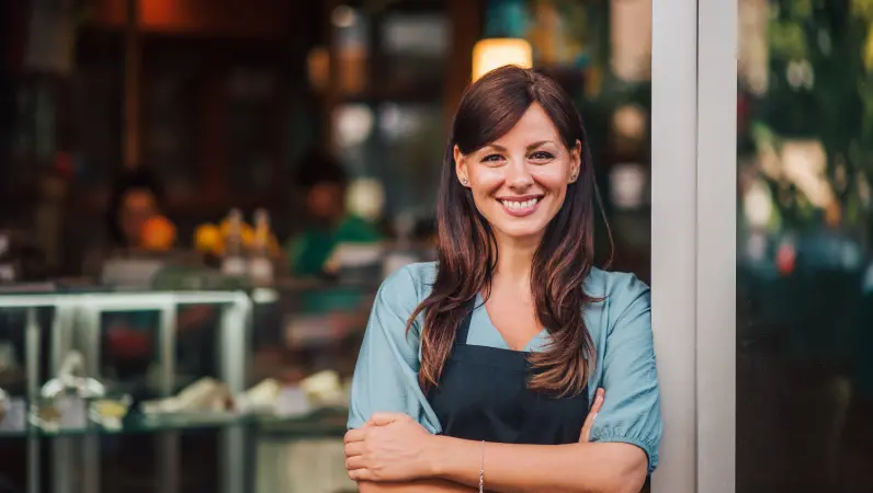A happy business owner smiles in front of cafe entrance. Find out how to pest-proof your business from the experts at Xceptional Wildlife.