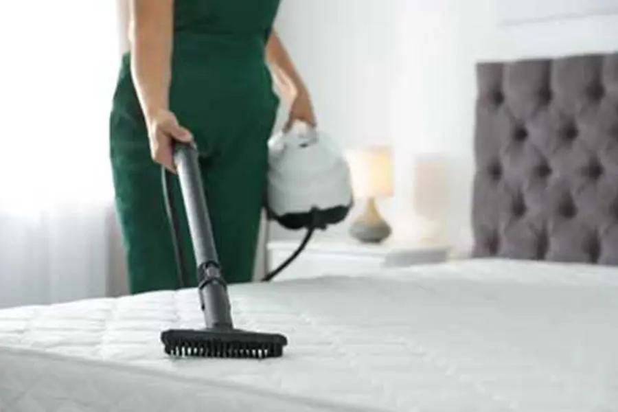 A person steam cleaning a mattress