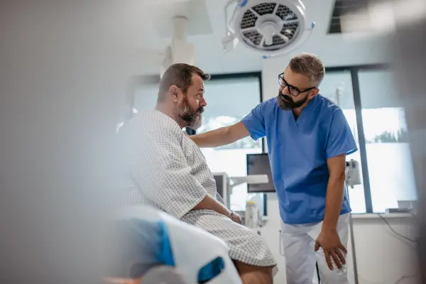 A doctor and a patient sitting in a treatment room, engaged in conversation.