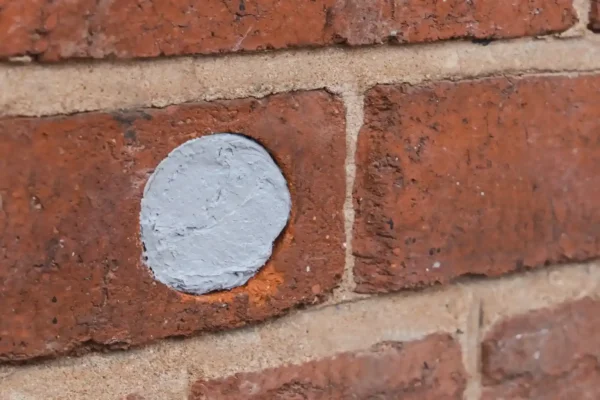 A hole in a brick wall that has been closed to prevent rodents from entering.